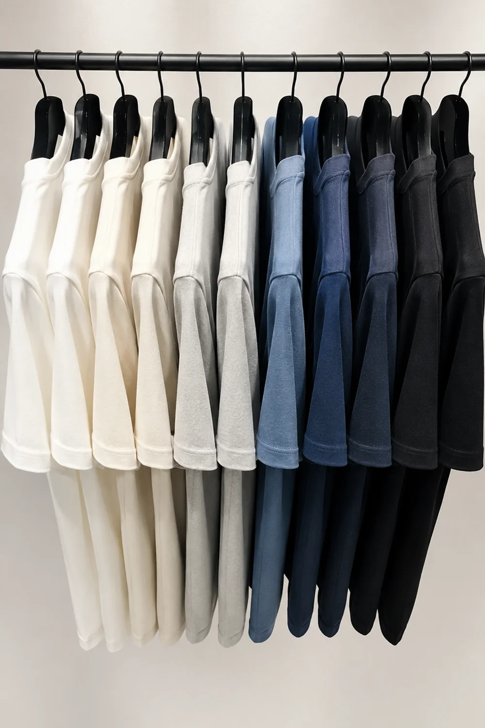 Closet hanging rail with clothes arranged in light-to-dark color gradient on uniform slim hangers