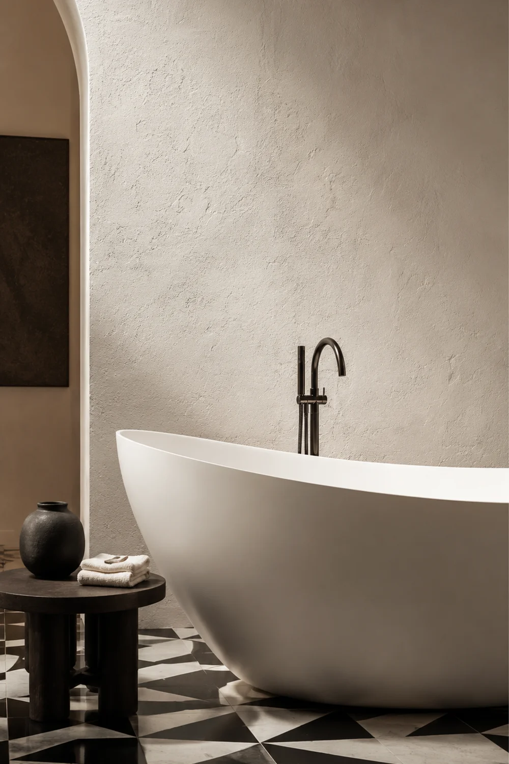 Freestanding white oval bathtub against black and white graphic floor tile