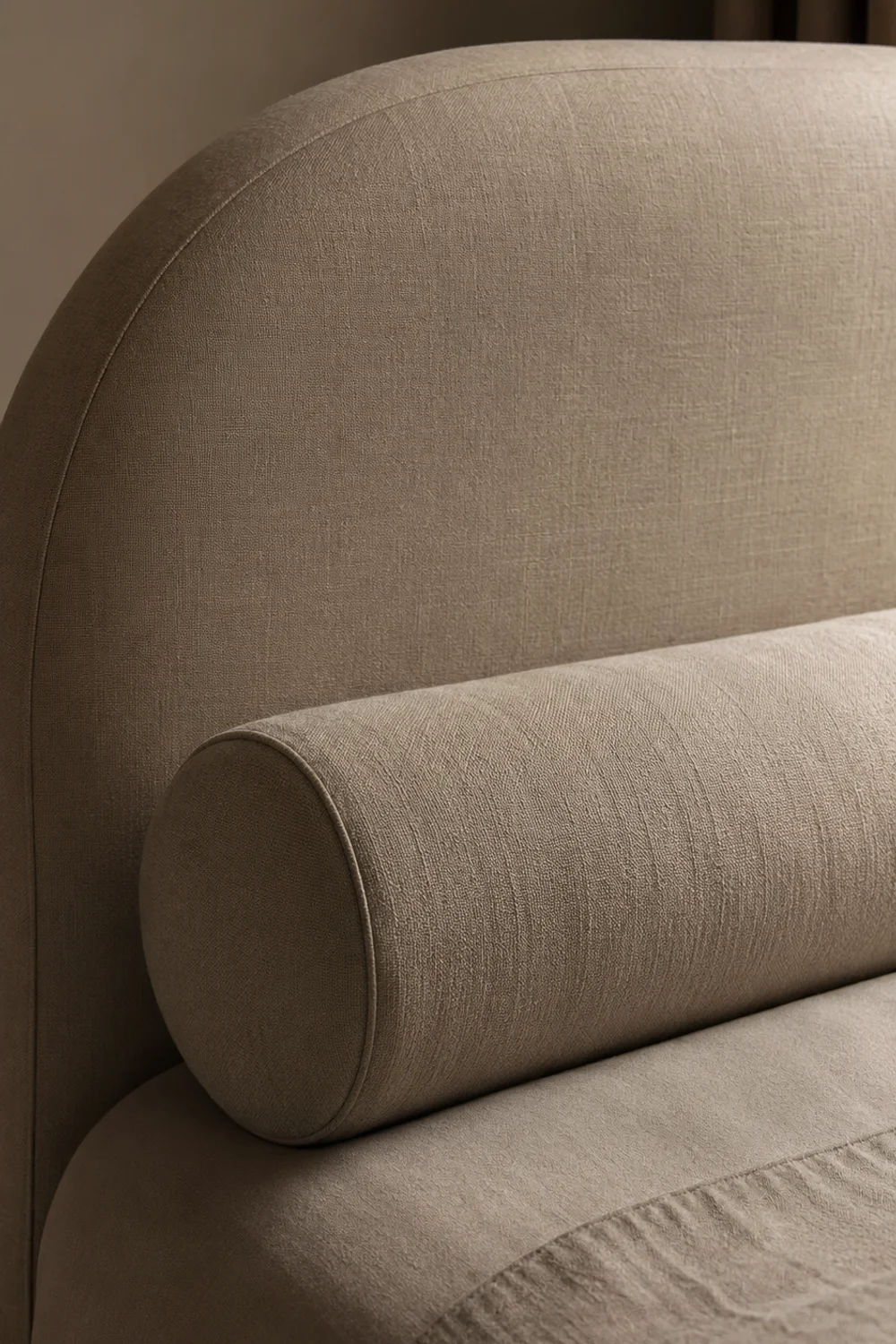 Cylindrical bolster pillow placed in front of a curved upholstered headboard