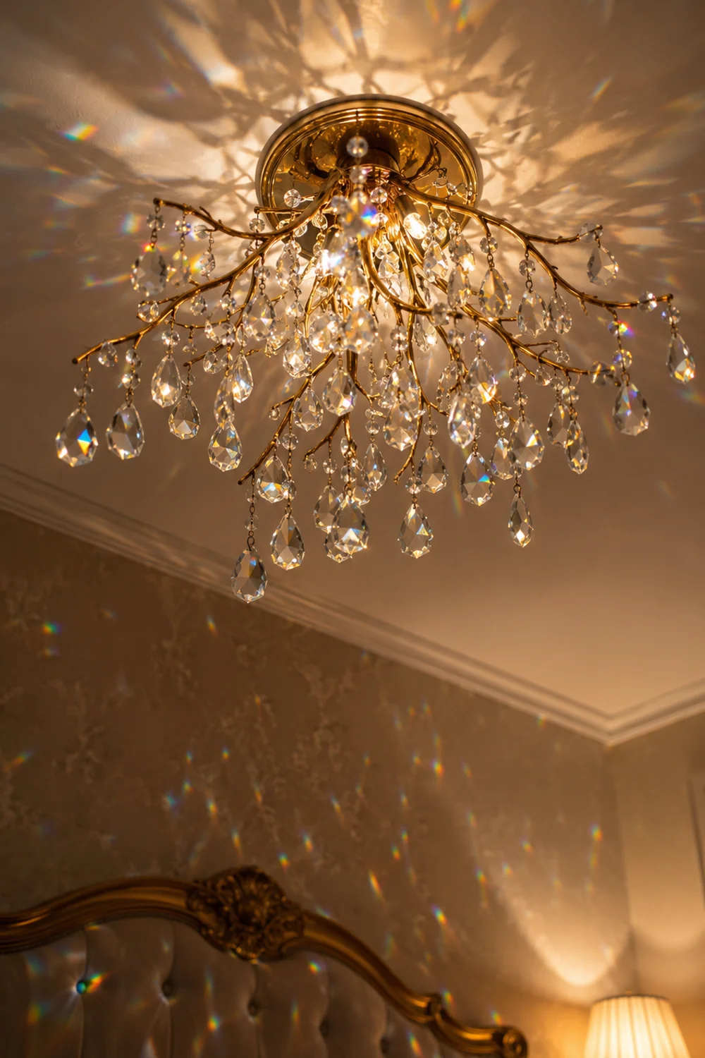 Small vintage-style crystal chandelier with aged brass frame casting light reflections on the ceiling