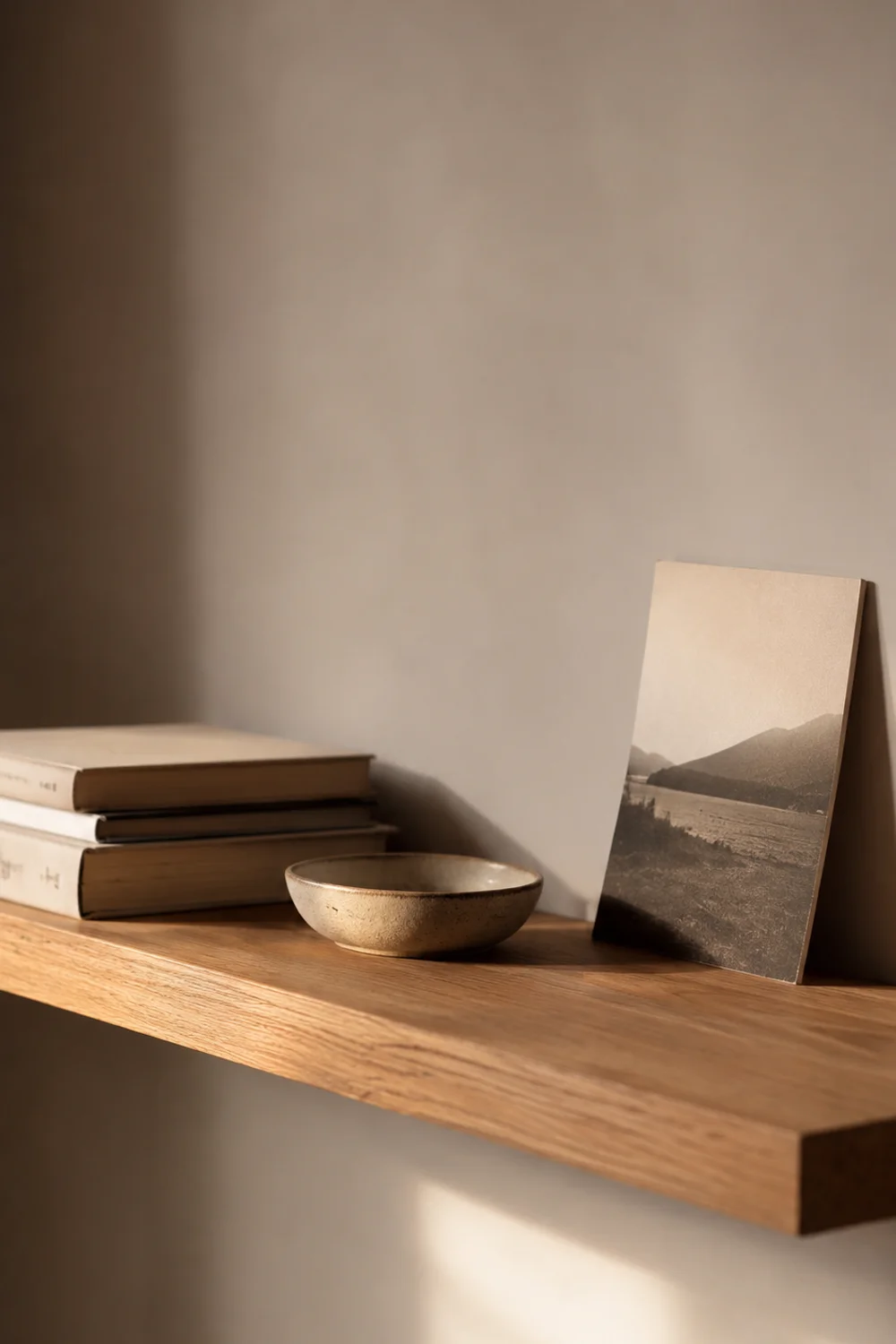 Narrow floating oak shelf styled with a few personal objects in a bedroom