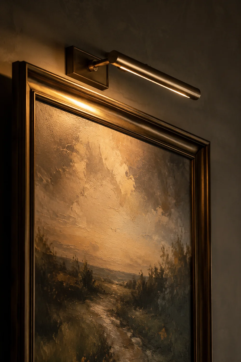 Small picture light grazing a framed art piece above a bedroom dresser