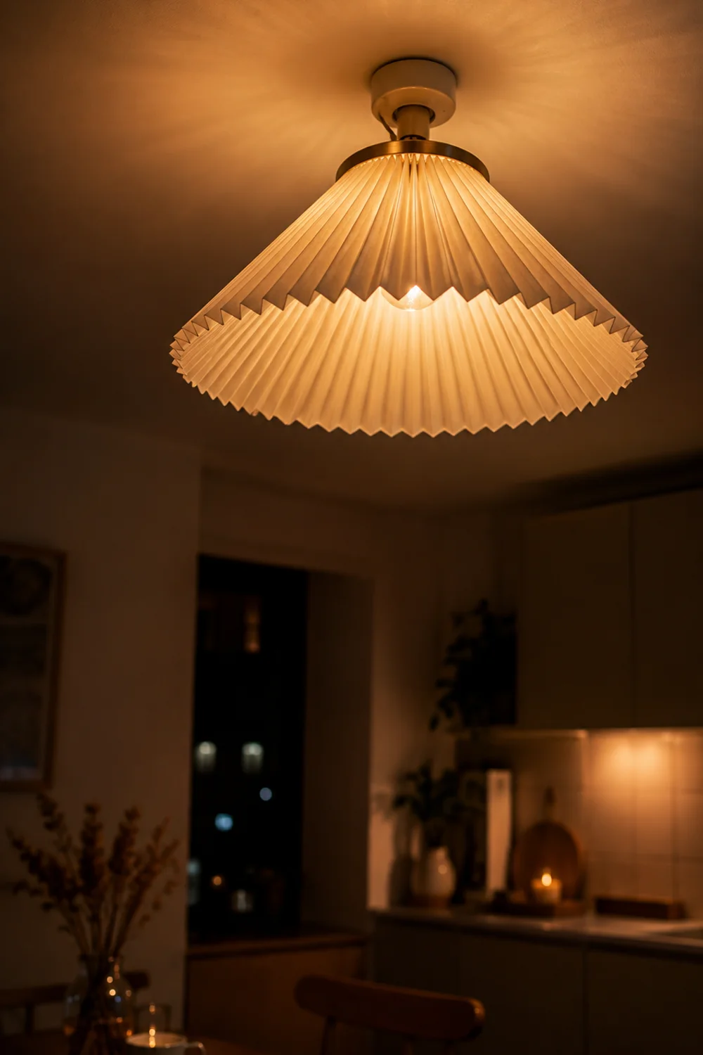 Clip-on pleated fabric lamp shade diffusing warm light over a small kitchen ceiling fixture
