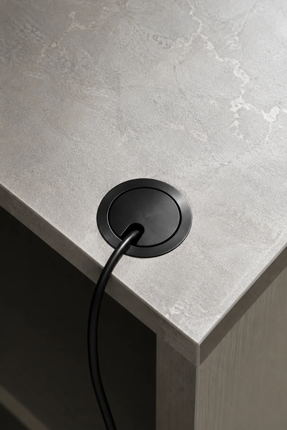 Countertop cord grommet routing an appliance cable into the cabinet below