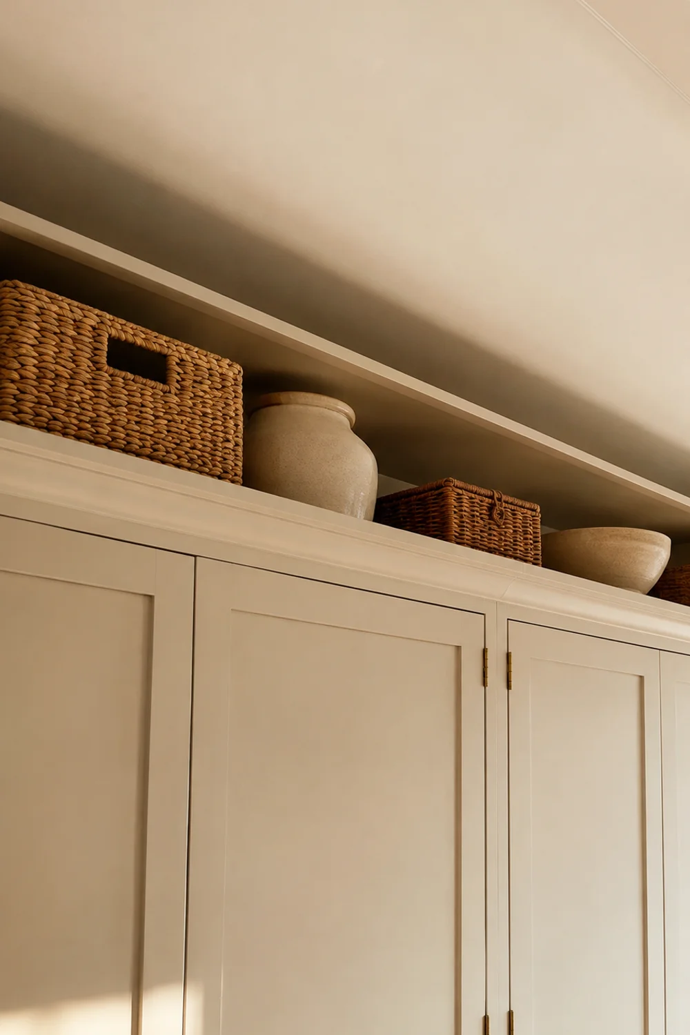 Painted wood riser shelf above kitchen cabinets matching the cabinet color, styled with storage containers