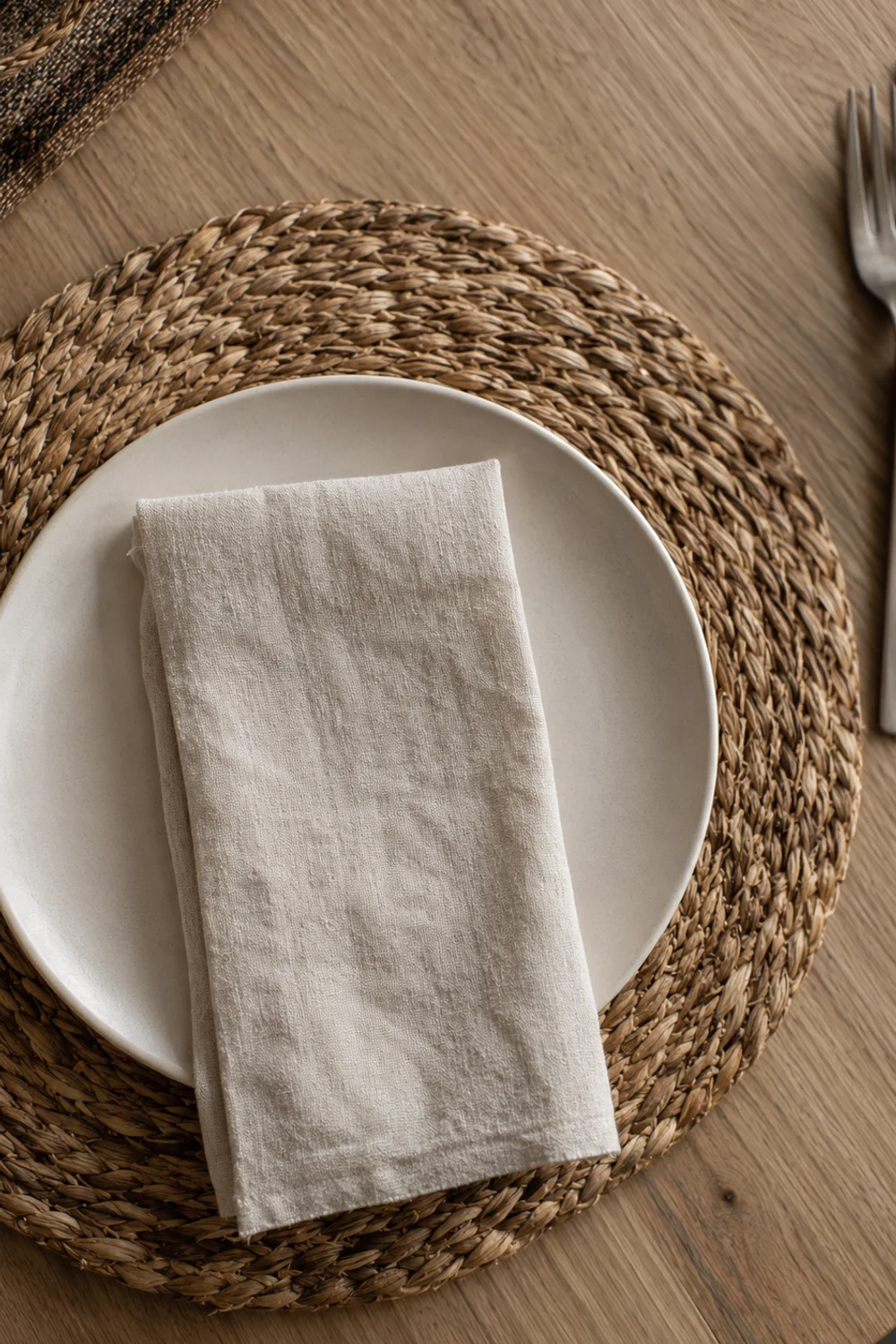 Overhead view of a woven corn husk placemat set beneath a plate on a modern fall table setting